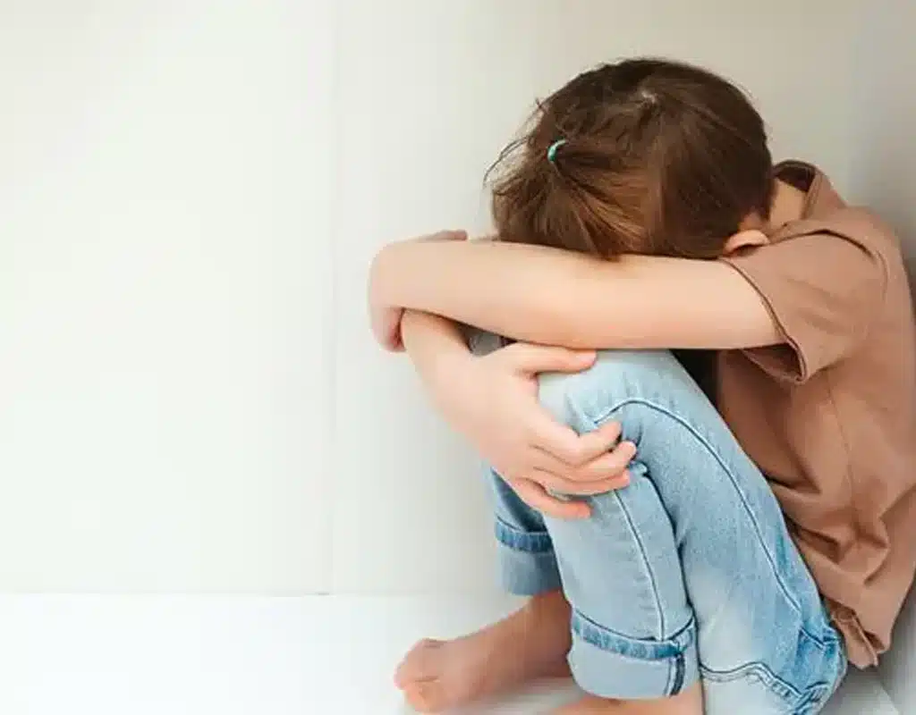 child sitting in a corner upset